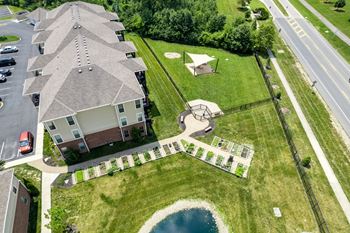 A bird's eye view of a residential area with houses, a playground, and a pond.